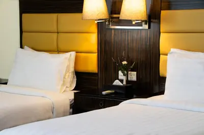 a hotel room with two beds and a yellow headboard at Fortune Karama Hotel in Dubai