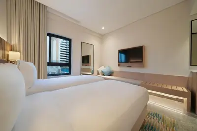 a bedroom with a large white bed and a tv at Arabian Park Dubai, an Edge by Rotana Hotel in Dubai