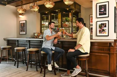 two men sitting at a bar drinking beer at Arabian Park Dubai, an Edge by Rotana Hotel in Dubai