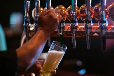 a person is holding a glass of beer at Jumeira Rotana – Dubai in Dubai