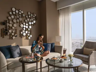 a woman sitting on a couch in a living room at Sofitel Dubai The Obelisk in Dubai