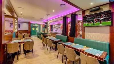 a restaurant with tables and chairs and a tv at Donatello Hotel in Dubai