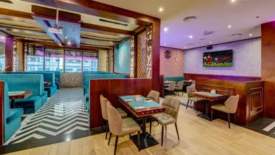 a restaurant with blue and purple walls and tables and chairs at Donatello Hotel in Dubai