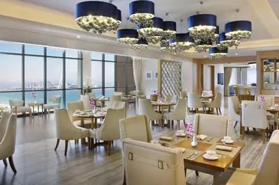 a restaurant with tables and chairs and large windows at Al Habtoor Grand Resort, Autograph Collection in Dubai