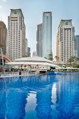 a large swimming pool with white umbrellas in a city at Al Habtoor Grand Resort, Autograph Collection in Dubai