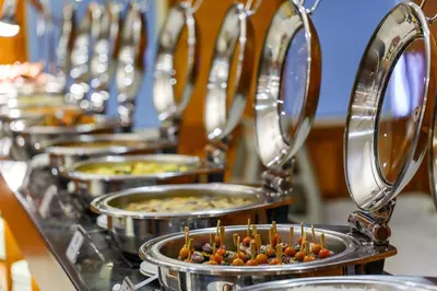 a row of metal pans filled with food on a counter at Grand Excelsior Hotel Bur Dubai in Dubai