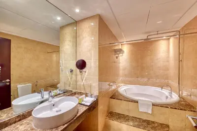 a bathroom with a large sink and a tub at Majestic City Retreat Hotel in Dubai