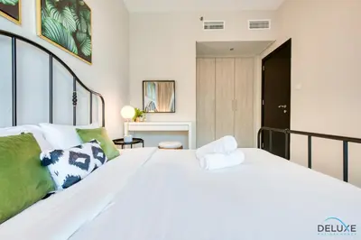 a bedroom with a large white bed with green pillows at Distance Away From Expo City Dubai 1BR Unit, MAG 510, Madinat Al Mataar by Deluxe Holiday Homes in Dubai