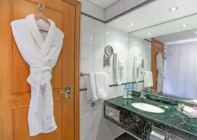 a bathroom with a sink and a towel hanging from a door at Millennium Plaza Downtown, Dubai in Dubai