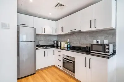 a kitchen with white cabinets and a stainless steel refrigerator at The Smart Concierge - Royal Oceanic in Dubai