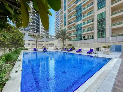a large swimming pool with purple chairs and buildings at The Smart Concierge - Royal Oceanic in Dubai