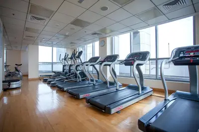 a row of treadmills in a gym with windows at Awesome Marina Canal View 1BD Bay Central Marina in Dubai