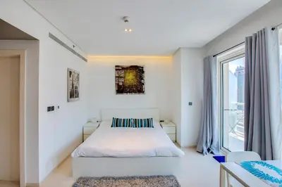 a white bedroom with a bed and a large window at Stylish Studio in West Avenue Dubai Marina in Dubai