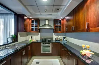 a kitchen with wooden cabinets and a sink at Durrani Homes - Designer 2BR Apt with stunning Burj khalifa and Fountain View in Dubai