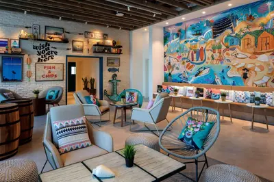 a restaurant with chairs and tables and a large mural at Rove La Mer Beach, Jumeirah in Dubai