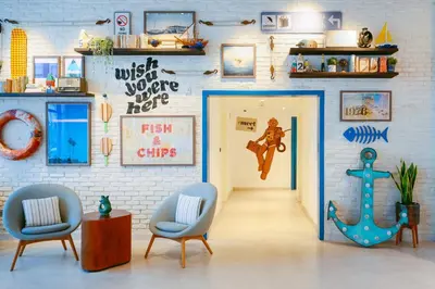 a room with a door and two chairs and a wall with signs at Rove La Mer Beach, Jumeirah in Dubai