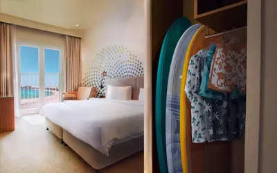 a hotel room with a bed and a surfboard at Rove La Mer Beach, Jumeirah in Dubai