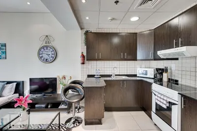 a kitchen with wooden cabinets and a clock on the wall at Sea View Studio 10min from beach Royal Oceanic in Dubai