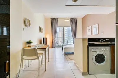 a kitchen and living room with a washing machine and a table at Splendid Studio in Marina View Towers in Dubai