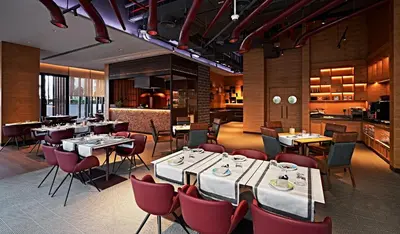 a restaurant with tables and chairs and a kitchen at Barcelo Business Bay Dubai in Dubai