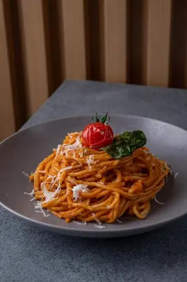 a plate of pasta with a tomato on a table at Element Al Jaddaf, Dubai in Dubai