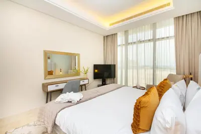 a white bedroom with a large bed and a television at Bespoke Holiday Homes - Palm Jumeirah- 2 Bedroom Sea View with Pool & Beach Access, The 8 in Dubai