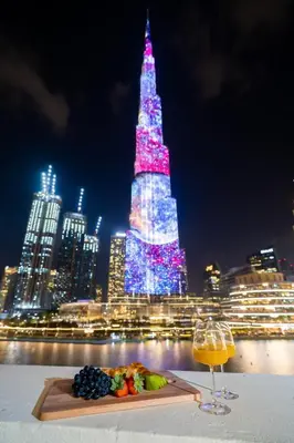 a table with a plate of food and a glass of wine at Durrani Homes - Heaven On Earth- Burj Khalifa Fireworks in Dubai