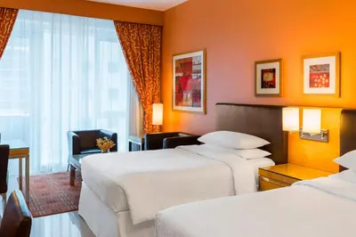 a hotel room with two beds and a chair at Four Points by Sheraton Bur Dubai in Dubai