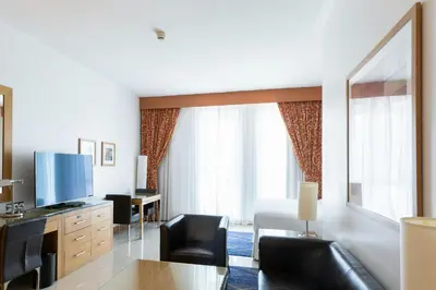 a hotel room with a living area with a television and chairs at Four Points by Sheraton Bur Dubai in Dubai
