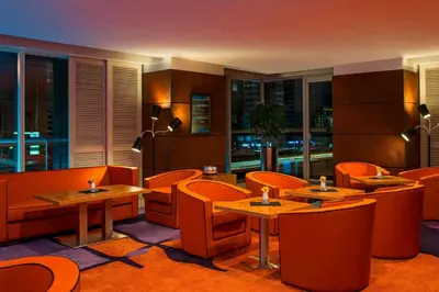 a restaurant with orange chairs and tables and windows at Four Points by Sheraton Sheikh Zayed Road in Dubai
