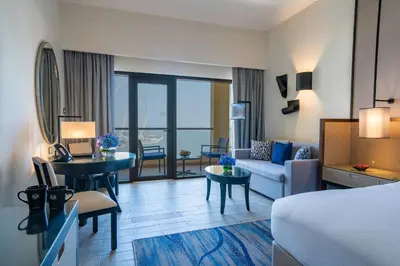 a hotel room with a bed and a living room at Amwaj Rotana, Jumeirah Beach - Dubai in Dubai