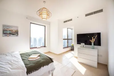 a white bedroom with a bed and a tv at Nasma Luxury Stays- Majestic Marina Views, Lavish 4BR Getaway in JBR in Dubai