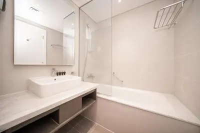 a white bathroom with a sink and a mirror at Luton Vacation Homes - Damac Maison Prive Studio, Canal View, Dubai - 16AB03 in Dubai
