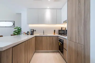 a kitchen with white counters and wooden cabinets at GuestReady Holiday Homes - A Sigh of Bliss in Dubai