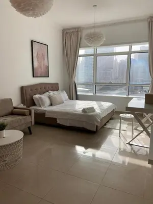 a bedroom with a bed and a couch and a window at skynest homes studio in JLT in Dubai