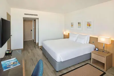a bedroom with a large white bed and a tv at JA Beach Hotel, Dubai in Dubai