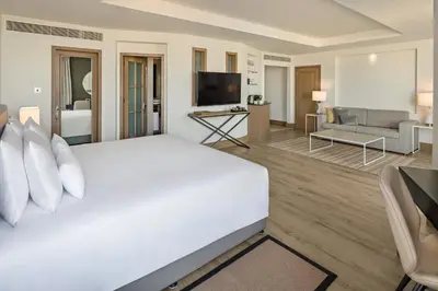 a bedroom with a large white bed and a living room at JA Beach Hotel, Dubai in Dubai