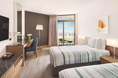 a hotel room with two beds and a desk at JA Beach Hotel, Dubai in Dubai