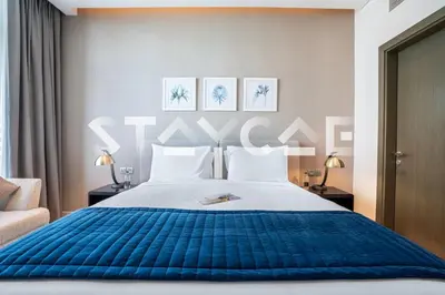a bedroom with a large bed with a blue blanket at Staycae Holiday Homes - Prive in Dubai
