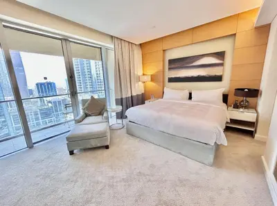 a hotel room with a bed and a chair and windows at Fashion Avenue Dubai Mall Residences - Studio with balcony in Dubai