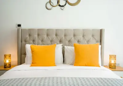 a bedroom with a bed with orange pillows and two candles at Nasma Luxury Stays - Boulevard Central Tower in Dubai