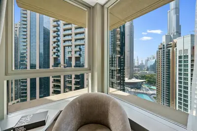a chair in a room with a view of a city at FIRST CLASS 3BR Burj Khalifa & Fountain View in Dubai