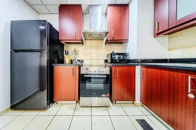 a kitchen with red cabinets and a black refrigerator at Brand new Rimal 2BD in front of The JBR Beach in Dubai
