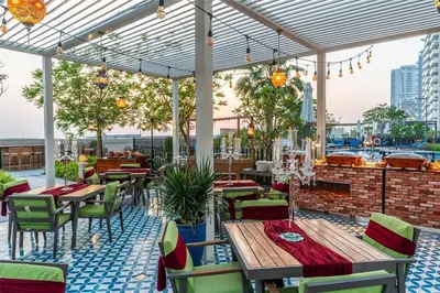 a patio with tables and chairs on a roof at Radisson Dubai Damac Hills in Dubai