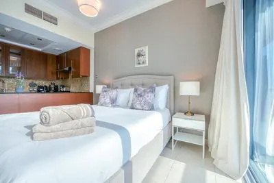 a bedroom with a large white bed and a kitchen at Prime Retreats - Downtown Dubai in Dubai