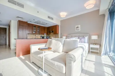 a living room with a white couch and a kitchen at Prime Retreats - Downtown Dubai in Dubai