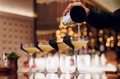 a person pouring a drink into a martini glass at The St. Regis Dubai, The Palm in Dubai