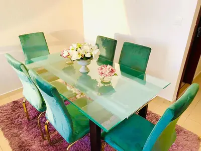 a dining room table with green chairs and flowers on it at Luxury Casa - Royal Sea View Apartment JBR Beach 2BR in Dubai