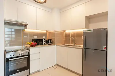 a kitchen with white cabinets and a stainless steel refrigerator at Blissful 1BR in Safi Town Square by Deluxe Holiday Homes in Dubai