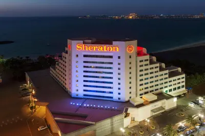 a hotel building with a sheraton sign on it at night at Sheraton Jumeirah Beach Resort in Dubai
